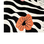 A vibrant area rug featuring a bold abstract design with black and white zebra-like stripes, accented by large, vivid orange floral patterns. The hand-tufted wool rug displays a modern artistic flair, perfect for adding a touch of elegance and style to any room.
