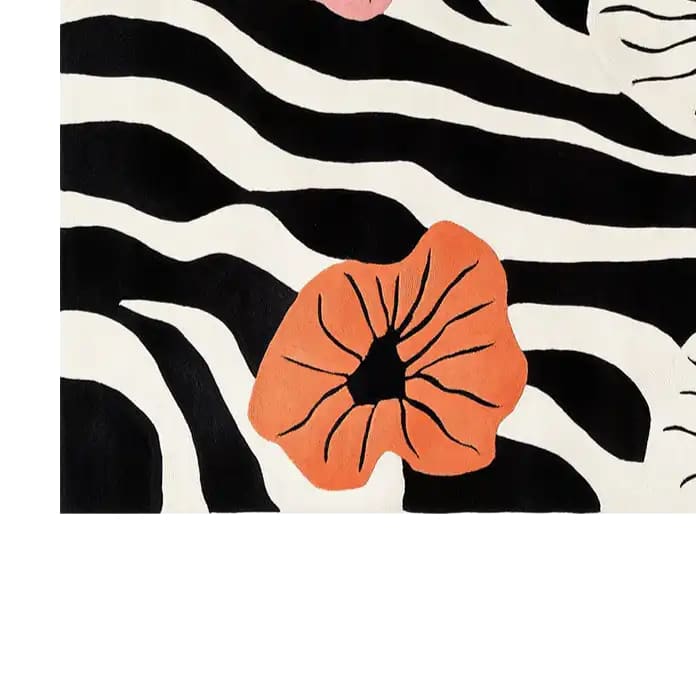 A vibrant area rug featuring a bold abstract design with black and white zebra-like stripes, accented by large, vivid orange floral patterns. The hand-tufted wool rug displays a modern artistic flair, perfect for adding a touch of elegance and style to any room.