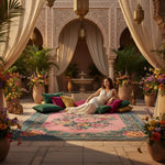 Woman in a white dress sitting on a colorful rug in an ornate courtyard with flowers and plants.