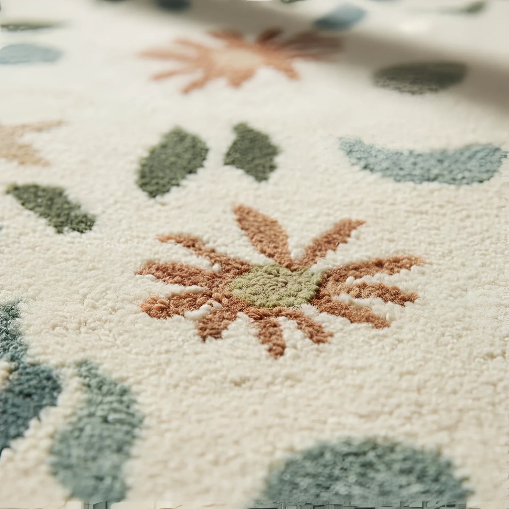 Close-up of a textured rug with floral patterns in green, brown, and beige.