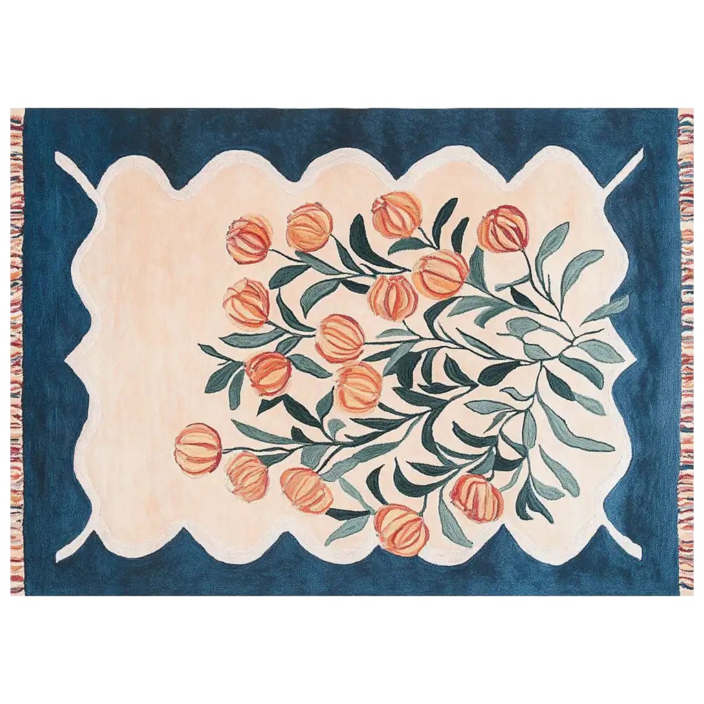 A beautifully hand-tufted wool area rug featuring a floral design with orange blossoms and green leaves on a soft beige background, surrounded by a deep blue border with scalloped edges. The Blossom Haven Sanctuary rug adds a touch of elegance and warmth to any room.
