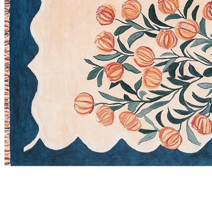 The Blossom Haven Sanctuary Hand Tufted Wool Area Rug features a vibrant floral design with orange blossoms and green leaves on a soft beige background. The intricate pattern is framed by a rich blue border, adding a touch of elegance and warmth to any room.