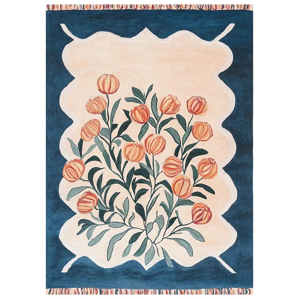 The Blossom Haven Sanctuary Hand Tufted Wool Rug features a vibrant floral design with orange blossoms and green leaves against a creamy beige background. The rug is bordered by a rich blue frame, adding a touch of elegance to any room. This area rug combines traditional craftsmanship with modern aesthetics.
