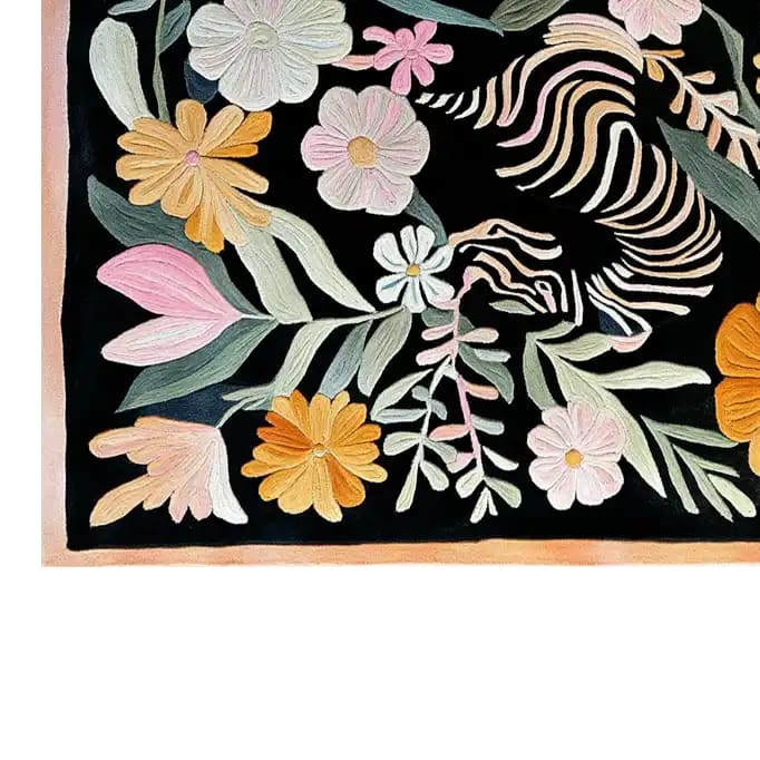 A detailed view of the Blossom Safari Hand Tufted Wool Rug, featuring a vibrant floral design with pink, orange, and white flowers against a dark backdrop. This area rug showcases intricate patterns and a soft texture, perfect for adding a touch of elegance to any room.