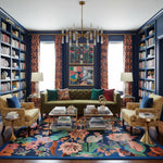 Decorative living room with a green sofa, colorful rug, and bookshelves.