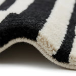 Close-up of a black and white striped rug with textured edges.