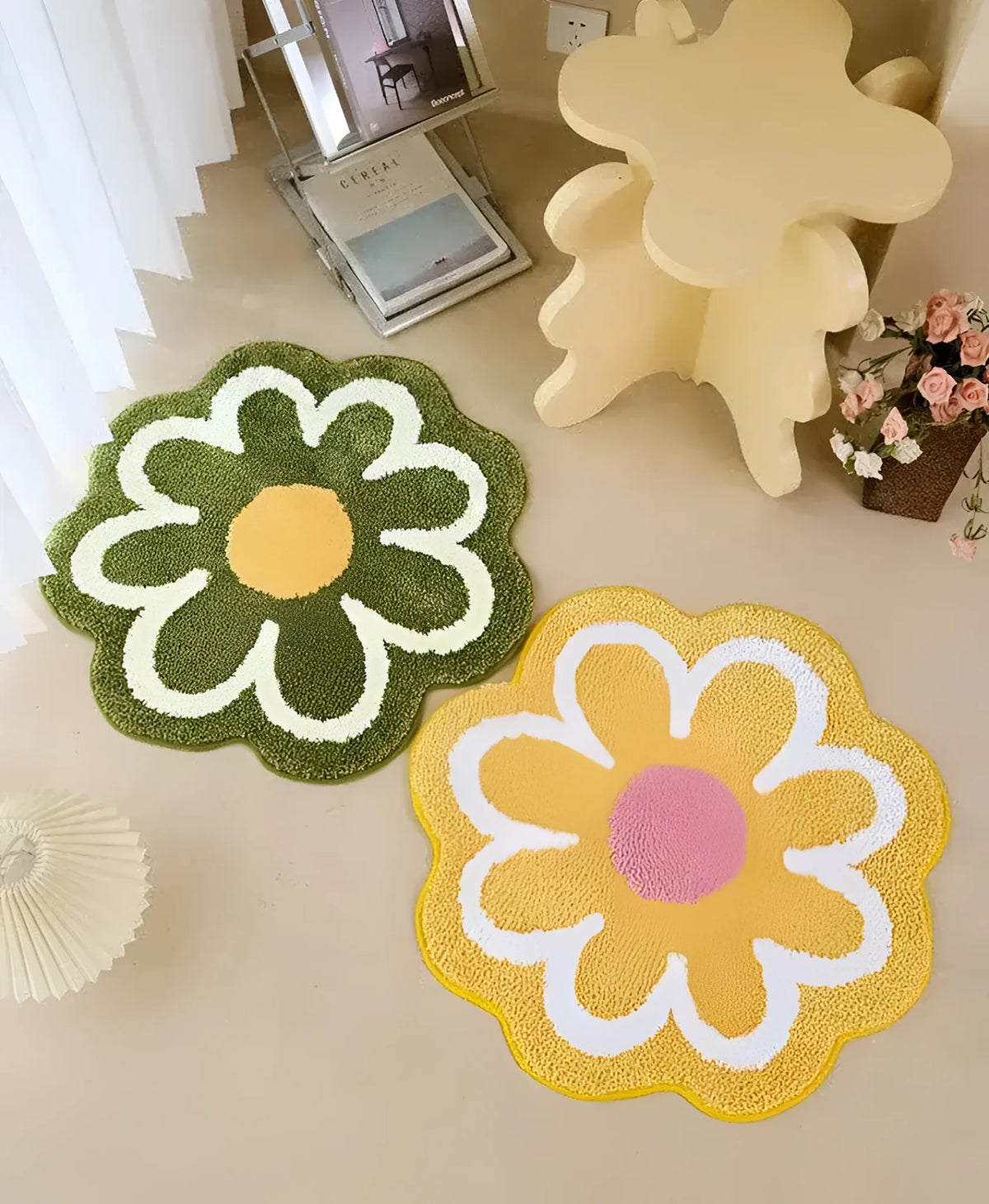 A charming image of two round area rugs shaped like blossoming flowers, adding a playful touch to a neutral-toned room. The green rug features a yellow center with white petals, while the yellow rug has a pink center with white petals. Perfect for enhancing any space with a touch of floral design.