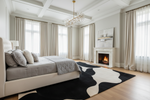 Modern bedroom with an abstract rug, bed, fireplace, and large windows.