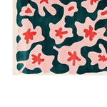 A vibrant area rug featuring an abstract floral pattern in bold red and soft pink against a deep teal background, showcasing a modern artistic design.