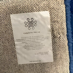 Close-up view of the back of the Blue Arctic Geo Modern Hand Tufted Wool Rug, highlighting the detailed weave and care instructions. Perfect choice for rugs for living room or dining room, this wool rug combines style and durability.