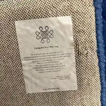 Close-up view of the back of the Blue Arctic Geo Modern Hand Tufted Wool Rug, highlighting the detailed weave and care instructions. Perfect choice for rugs for living room or dining room, this wool rug combines style and durability.