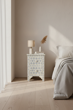 Blue bee pattern 2 drawer nightstand in white, styled with a small lamp beside a bed.