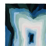 Top view of the Blue Depth Vortex Hand Tufted Rug showcasing its contemporary, abstract design. Ideal for living rooms, this wool area rug features swirling shades of blue, green, and cream, adding a modern touch to your interior decor.