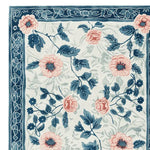 A close-up view of the Blush Garden Bloom Hand Tufted Area Rug, showcasing its intricate floral design with pink and blue flowers on a soft wool texture. Perfect for adding a touch of elegance to your living room, this floral rug combines beauty and comfort.