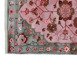 Close-up view of the Blush Medallion Knotted Wool Rug, showcasing intricate floral patterns in pink and brown tones on a soft blush background, framed by a detailed blue-green border with floral motifs.