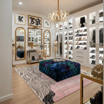 Luxury closet with high-end shoes, mirrors, a pink abstract hand-tufted wool rug, and decorative items.