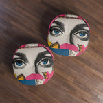 Two Bold Floral Portrait Floor Pillows from above on dark wood floor showing colorful blue eyes floral collage pattern