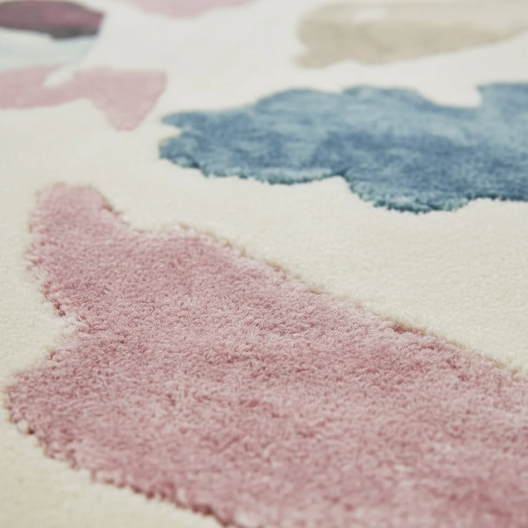 Close-up of a soft, textured rug with pink, blue, and white colors.