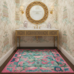 Decorative bathroom with ornate gold mirror, sink, and floral-patterned rug.