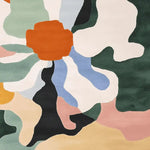 Vibrant and contemporary area rug with an abstract floral design, featuring bold colors like orange, green, blue, and white, perfect for adding a modern touch to living room spaces. This hand-tufted wool rug serves as a striking square area rug, ideal for those seeking unique rugs for their living room decor.