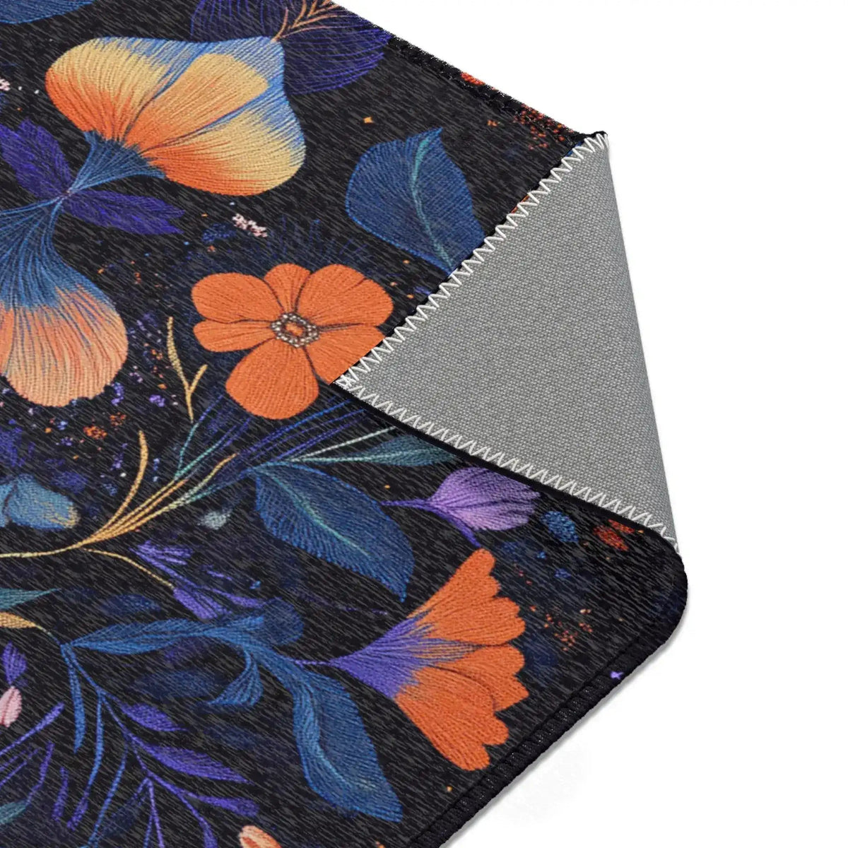 Botanical Bliss Floral Design Accent Rug corner fold with orange poppies, yellow-peach blooms and blue-purple leaves, grey backing