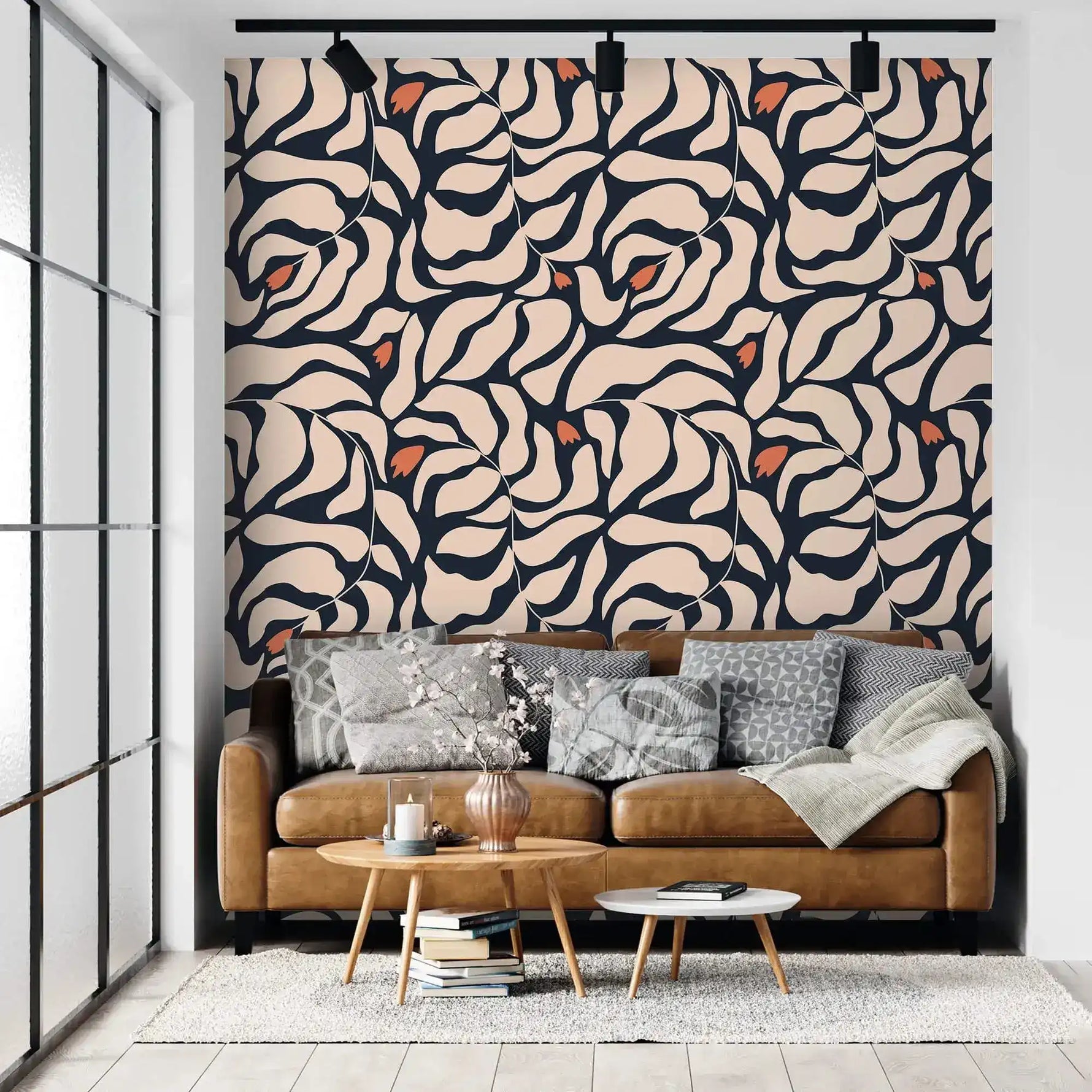Botanical extravaganza wallpaper behind tan leather sofa; cream and navy abstract oversized leaves with orange accents