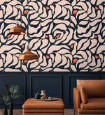 Botanical extravaganza wallpaper above navy panels with tan leather armchair, ottoman, and pair of copper pendant lights