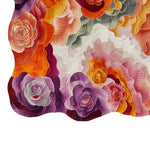 A vibrant, hand-tufted wool area rug featuring an abstract floral design with layers of colorful petals in shades of purple, orange, and pink. The intricate pattern creates a striking visual effect, making this area rug a bold centerpiece for any room.