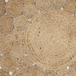 The Bria Natural Jute Round Area Rug features a unique circular design with intricate woven patterns, ideal for adding a rustic touch to your dining room. This large area rug is perfect for placing under a dining table or enhancing the coziness of your living room. The natural fibers of this Jute rug not only offer durability but also complement a variety of home decors.