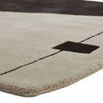 Close-up of a textured rug with a black square and stitching detail.