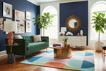 Modern living room with a green sofa, colorful contemporary geometric rug, and decorative elements.