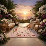 Woman relaxing on a lounge chair in a luxurious outdoor setting with a handmade floral pink rug, flowers and sunset.