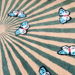 A beautifully crafted hand-tufted wool area rug featuring a vibrant design of butterflies over a radiating pattern. Perfect for adding a touch of elegance to living room and dining room spaces, this round rug showcases earthy tones, making it an ideal centerpiece for your living room area. The detailed butterfly motif enhances the natural charm of this dining room wool rug.