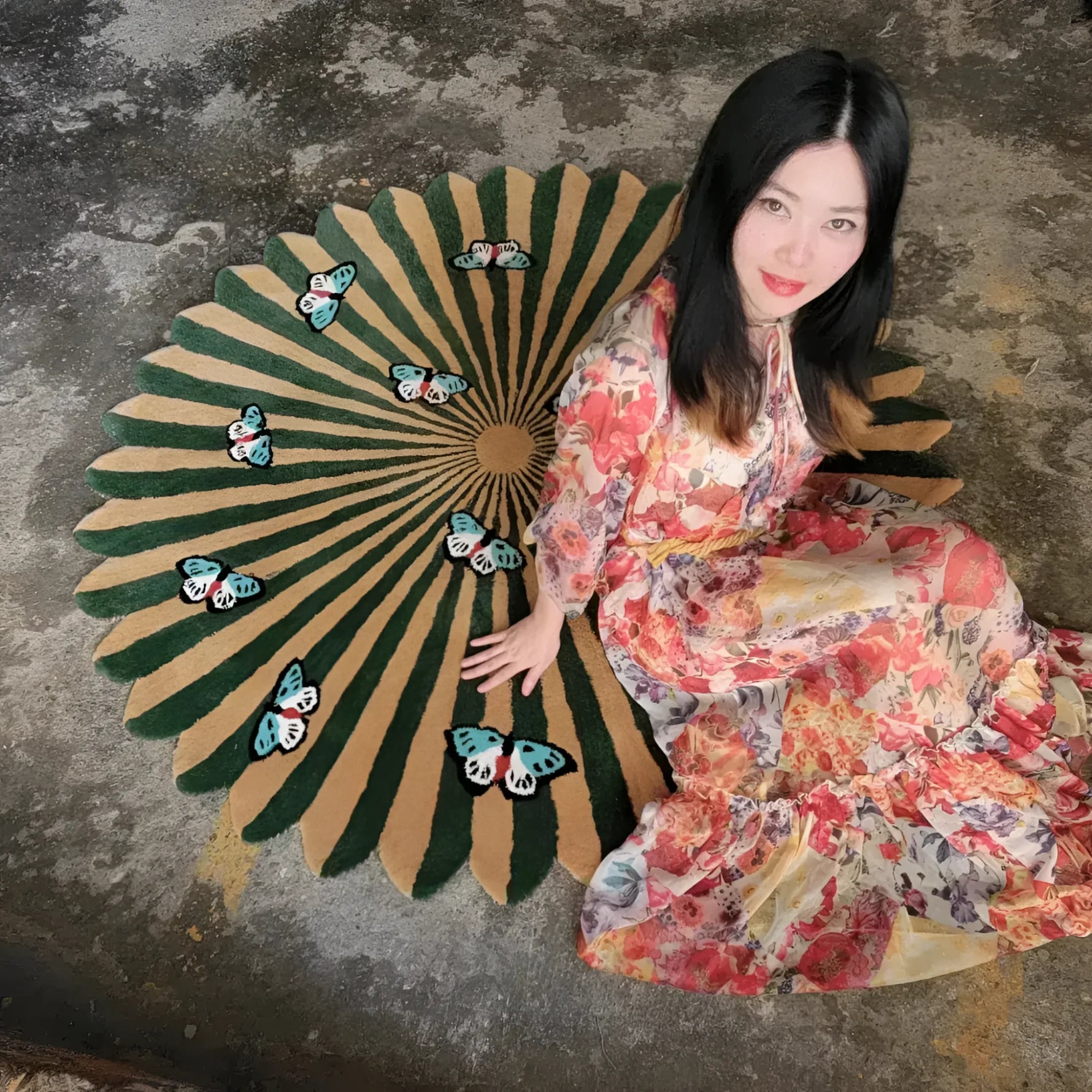 Colorful living room area rug featuring a round design with earthy tones and butterfly motifs, perfect for dining room decor. A woman in a floral dress sits elegantly on this hand-tufted wool rug, highlighting its unique design and vibrant colors.