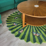 A vibrant green wool rug with butterfly motifs placed under a wooden round coffee table. This hand-tufted area rug adds a touch of nature and elegance, making it ideal for large living rooms and offices.