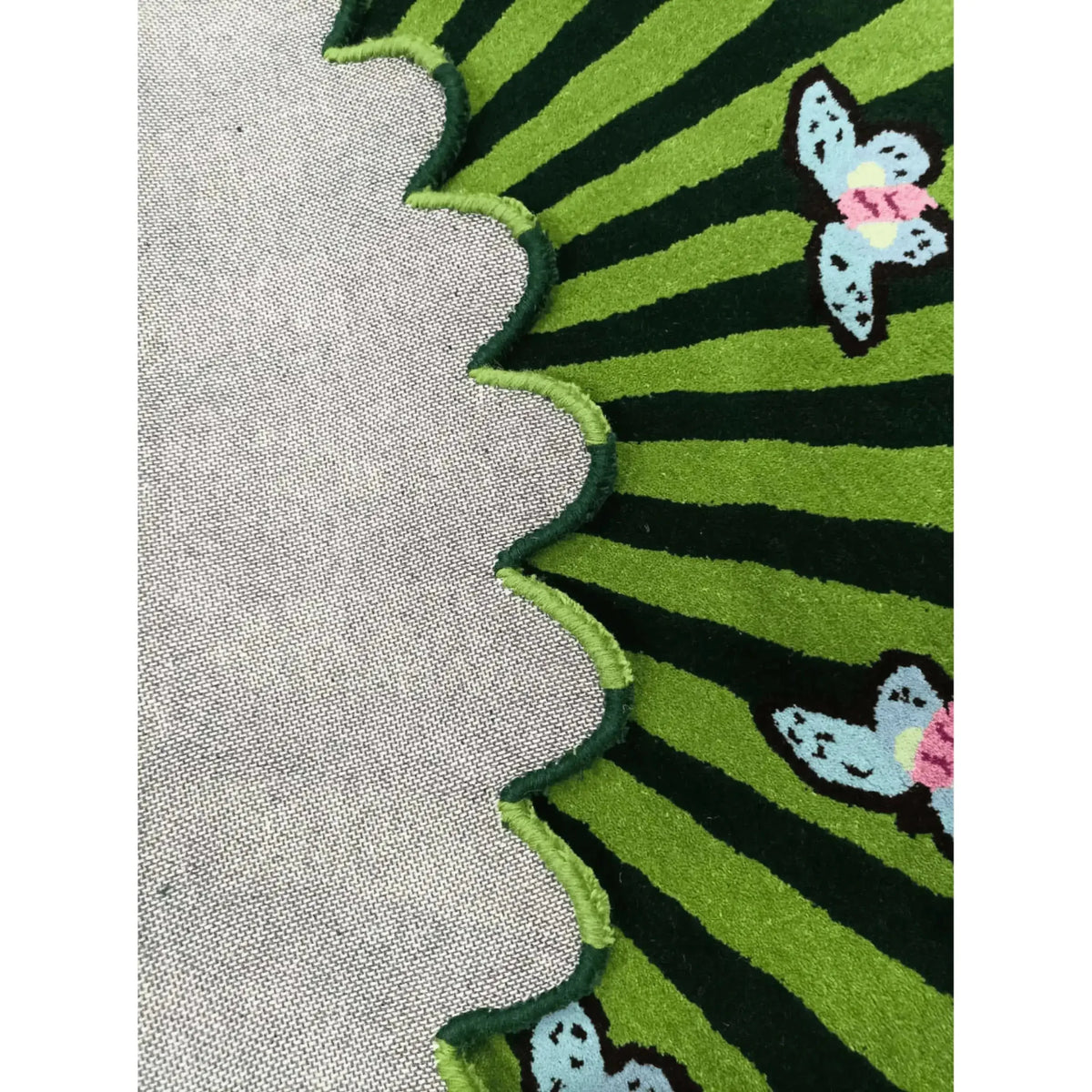 Close-up of the Butterflies over Flower Hand Tufted Wool Rug in green, showcasing a vibrant design with butterflies and a scalloped edge. Perfect for adding a touch of nature to your office or large living room. This area rug features a durable wool texture, ideal for living room decor.