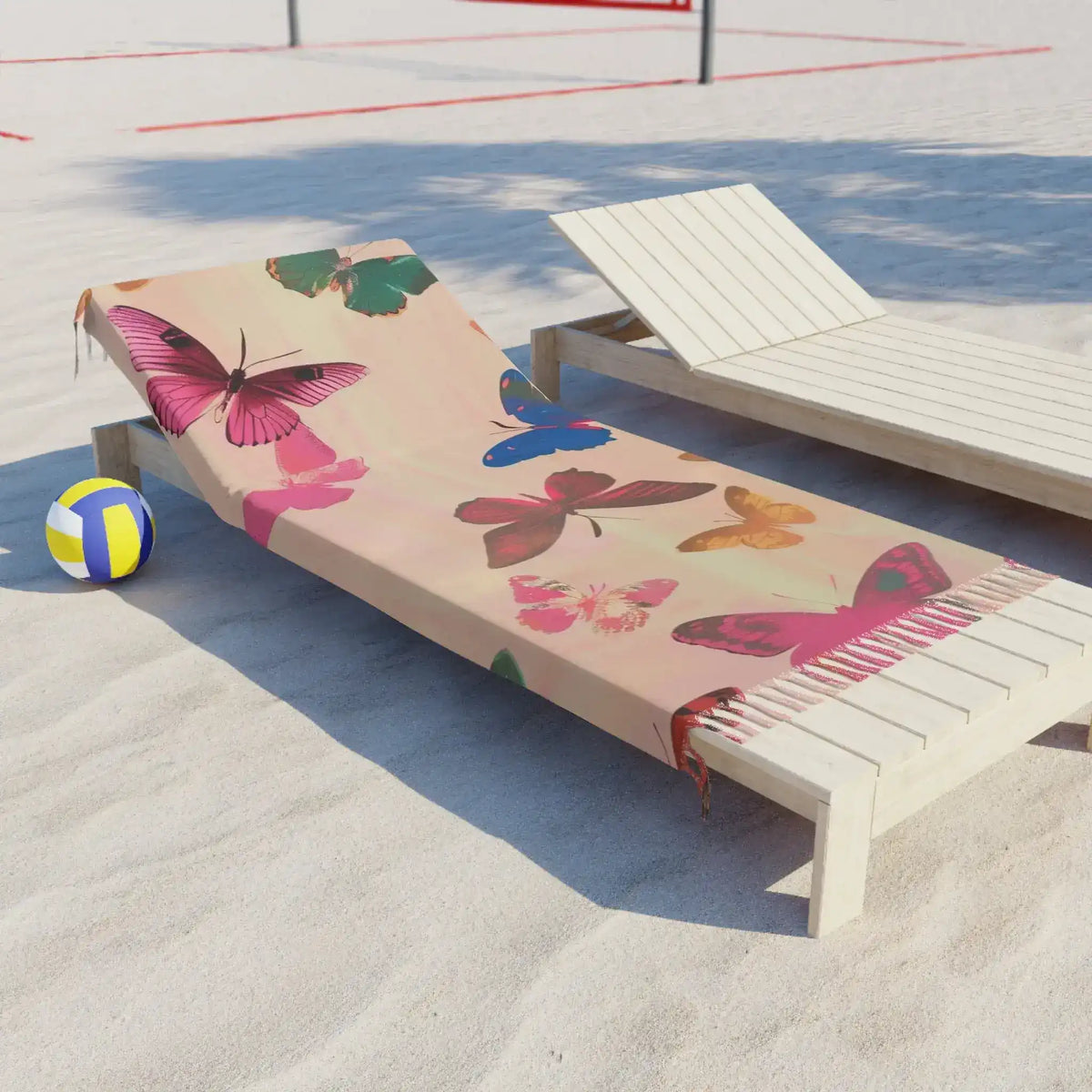 Butterfly Dreamscape Pink Beach Towel draped over white lounge chair on sandy beach with volleyball