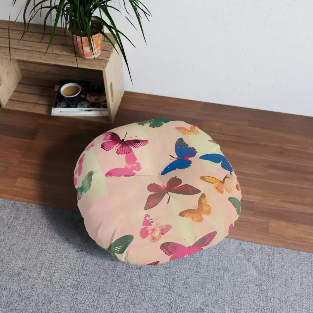 Butterfly Kisses Dreamy Pink Flight Floor Pillow styled in a bright room next to wooden shelving and plant, showing round shape and butterfly print