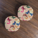 Two square Butterfly Kisses Dreamy Pink Flight Floor Pillows on hardwood floor overhead view with colorful butterfly pattern across blush fabric