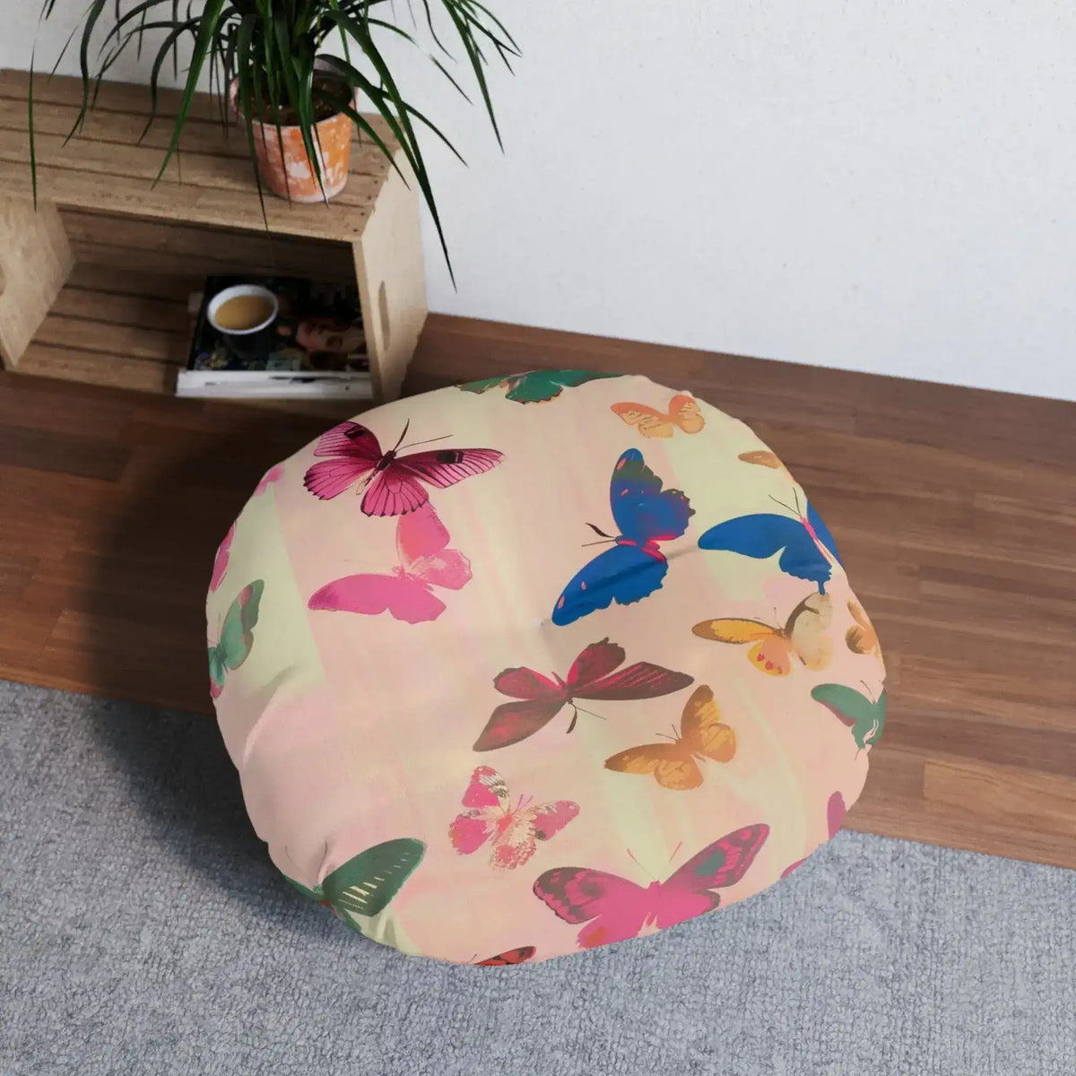 Butterfly Kisses Dreamy Pink Flight Floor Pillow in a room setting on wood floor near shelves and plant from lower angle showing full round profile