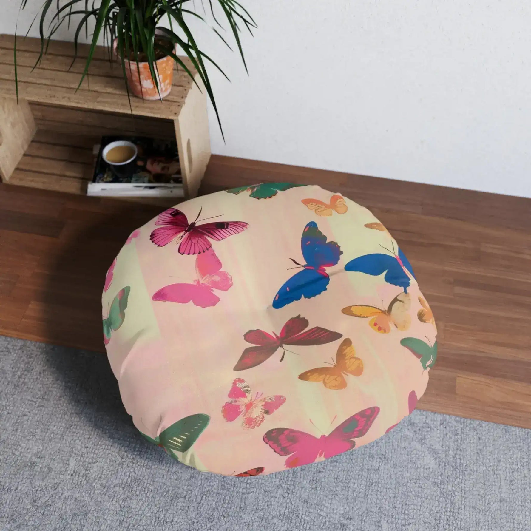 Butterfly Kisses Dreamy Pink Flight Floor Pillow in a room setting on wood floor near shelves and plant from lower angle showing full round profile
