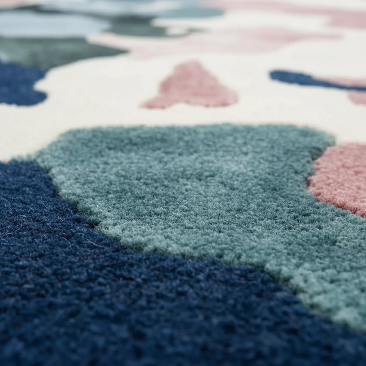 Close-up of a colorful geometric-patterned rug with blue, pink, and green colors.