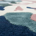 Close-up of a colorful geometric-patterned rug with blue, pink, and green colors.