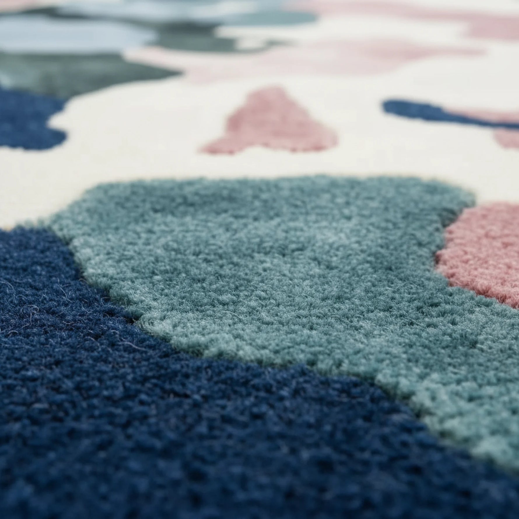 Close-up of a colorful geometric-patterned rug with blue, pink, and green colors.