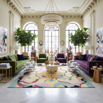 Luxurious living room with colorful rug, green sofa, purple armchair, and decorative items.