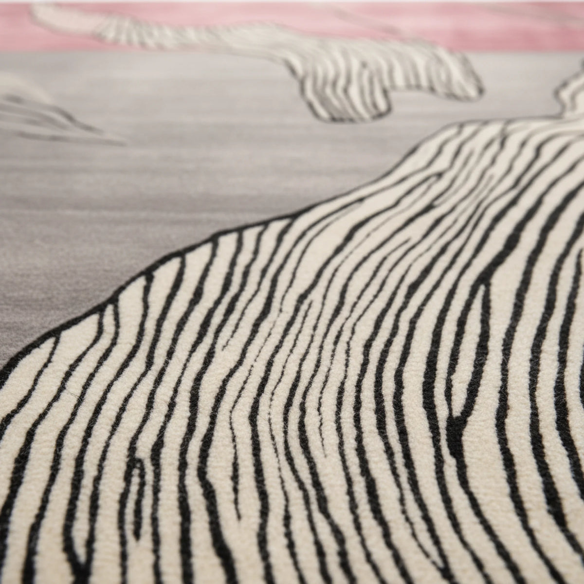 Close-up of a zebra-patterned rug with black and white stripes on a pink and gray background.