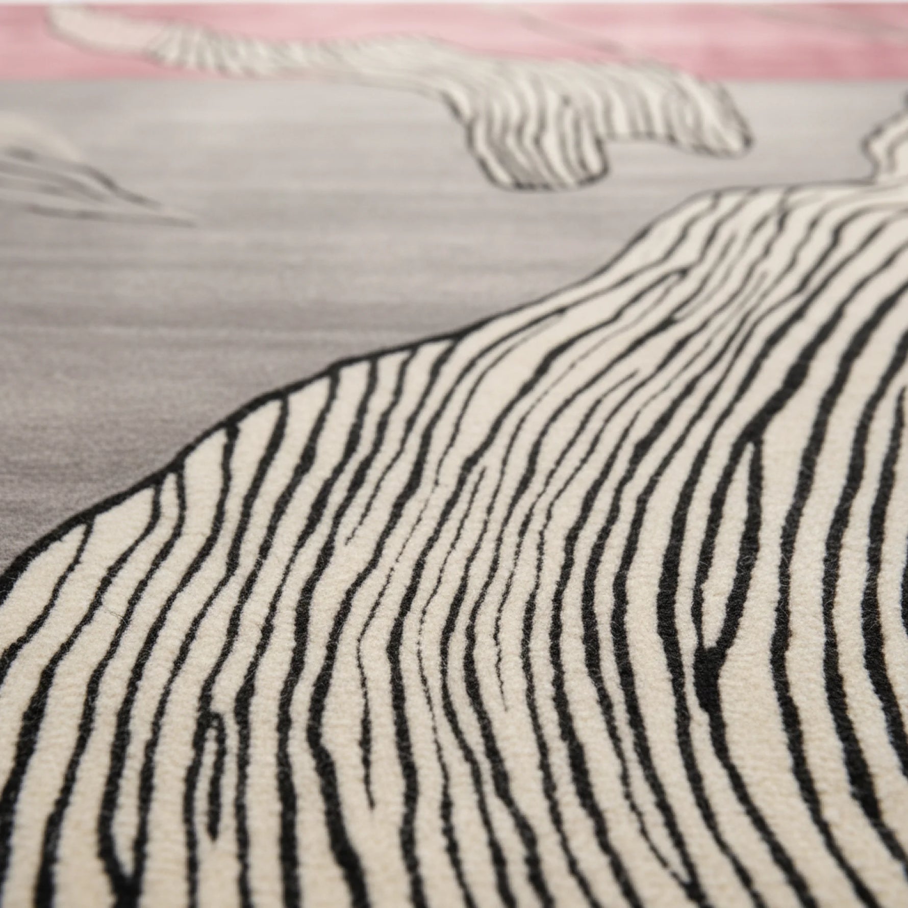 Close-up of a zebra-patterned rug with black and white stripes on a pink and gray background.