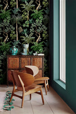 Carved wood cabinet and wooden chairs against jungle foliage wallpaper with green palms