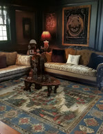 A beautifully styled living room featuring a Castle Country Wool Hand Knotted Area Rug. This vintage rug in the size of 8x10 graces the floor, showcasing intricate designs and rich colors. The rug complements the elegant furniture and decor, perfect for anyone looking to enhance their living room area with a touch of classic charm.