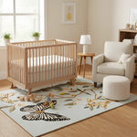 Nursery room with wooden crib, rug with butterfly design, and armchair.